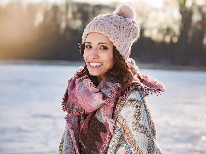 Frau trägt eine Mütze in einer Winterlandschaft | © gettyimages.de /Westend61