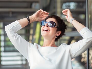 Frau mit kurzen haaren und Sonnenbrille freut sich. | © istockphoto.com, HbrH