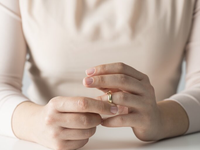 Frau macht ihren Ehering ab. | © iStock | solidcolours