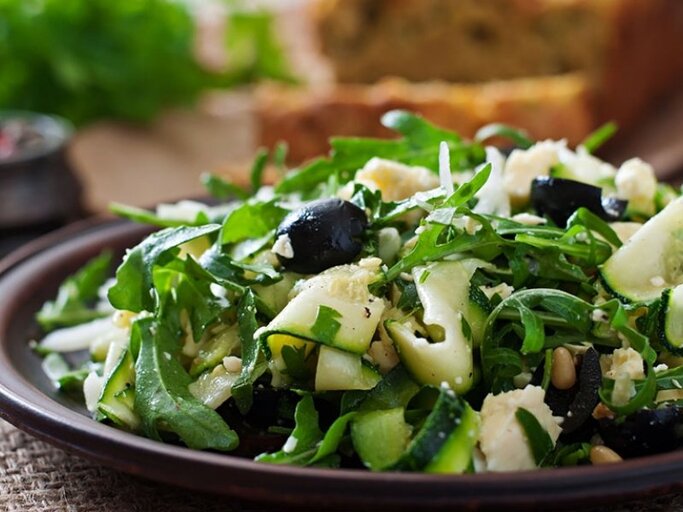 Dank ihres hohen Wassergehalts ist die Zucchini eine gute Grundlage für leichte Sommersalate – und schmeckt wunderbar zu Rucola, Oliven und Pinienkernen. | © Shutterstock | Timolina