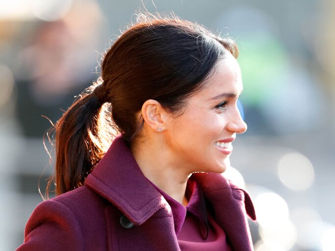 Meghan Duchess of Sussex mit Pferdeschwanz und weinrotem Mantel | © Getty Images | Max Mumby/Indigo