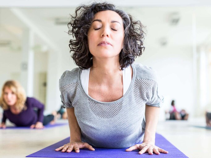Reife Frau macht eine Dehnungsübung beim Yoga | © iStock | alvarez