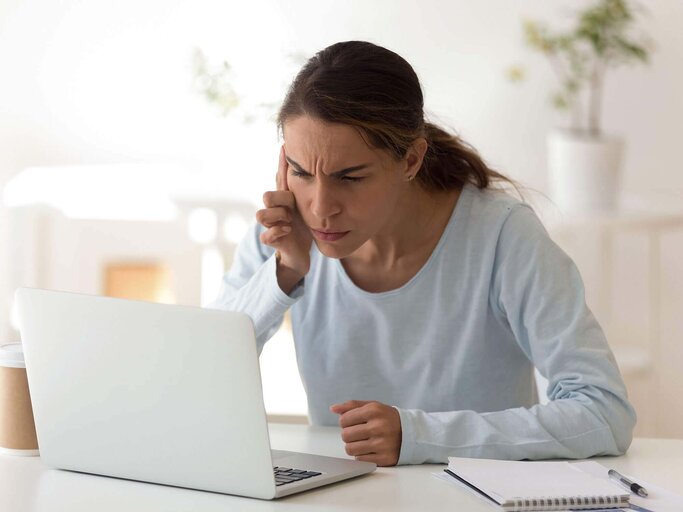 Frau sitzt am Laptop und kneift die Augen zusammen | © iStock | fizkes