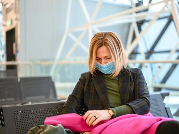 Frau sitzt mit Mundschutz während Corona in einer Wartehalle. | © iStock | ti-ja