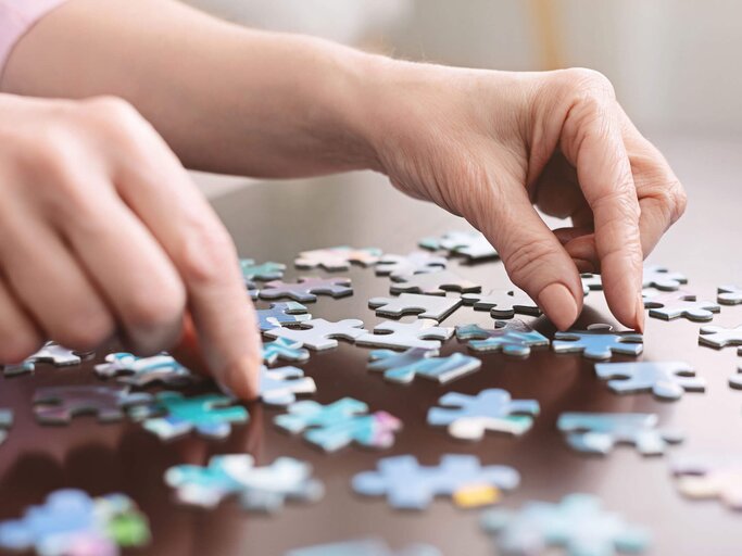 Die Hände einer älteren Frau üben ein Puzzle. | © iStock | Prostock-Studio