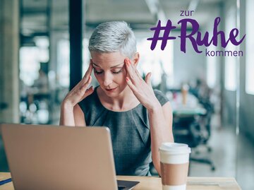 Frau mit kurzen grauen Haaren sitzt am Arbeitsplatz und ist gestresst. | © iStock | VioletaStoimenova