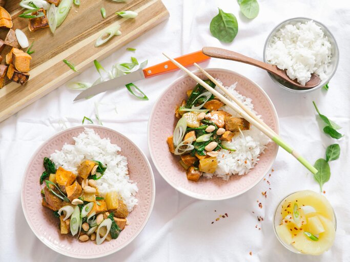Gelbes Curry mit Süßkartoffeln und Ananas und Reis in zwei Schalen auf einem Tisch mit weißer Tischdecke.  | © Fairtrade Original