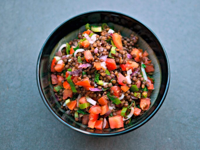 Frischer Linsensalat mit aufgeschnittenen Tomaten und Zwiebeln in einer Schüssel. | © iStock.com / Eleonora Tuveri