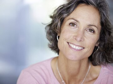 Schöne reife Frau mit Locken und Sommersprossen im Gesicht. | © iStock.com / laflor