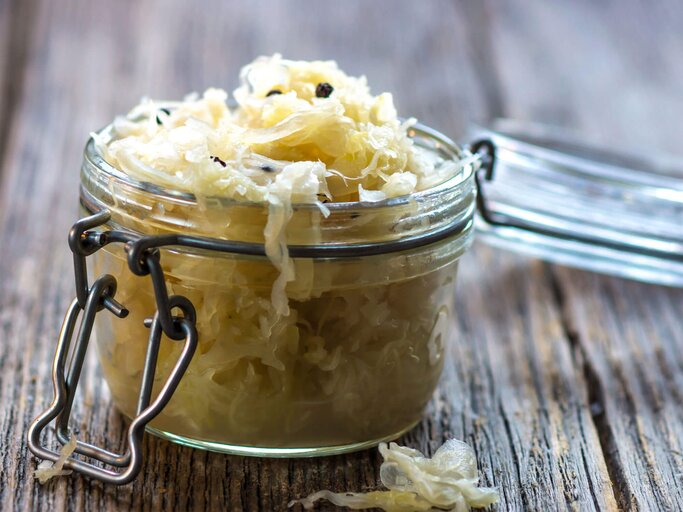 Glasgefäß gefüllt mit Sauerkraut auf einem rustikalen Holztisch. | © iStock.com / zeleno