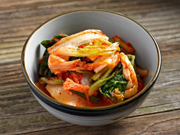 Schüssel mit Kimchi steht auf einem braunen Holztisch | © iStock.com / 4kodiak