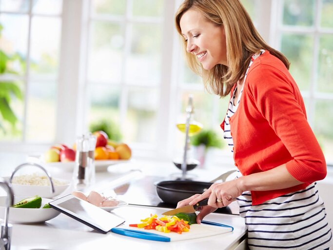 Frau steht in der Küche und bereitet ein gesundes Essen zu. | © iStock.com / monkeybusinessimages