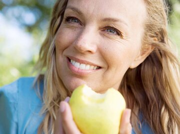 Frau ist an der frischen Luft und isst einen Apfel. | © gettyimages.de / Soren Hald