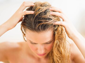Frau mit nassen Haaren, die ihre Kopfhaut berührt. | © gettyimages.de / Tetra Images