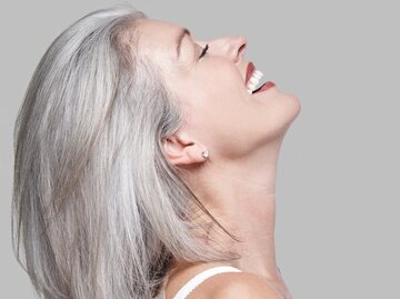 Frau mit grauen Haaren lacht. | © gettyimages.de / Mint Images