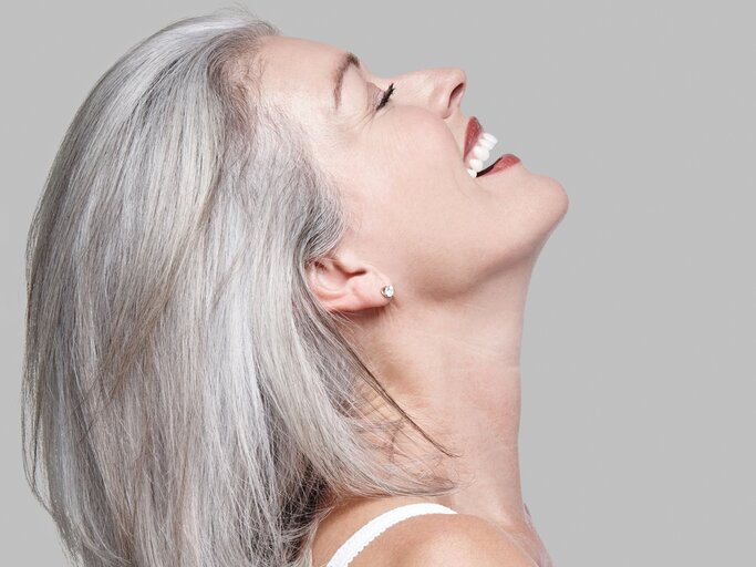 Frau mit grauen Haaren lacht. | © gettyimages.de / Mint Images