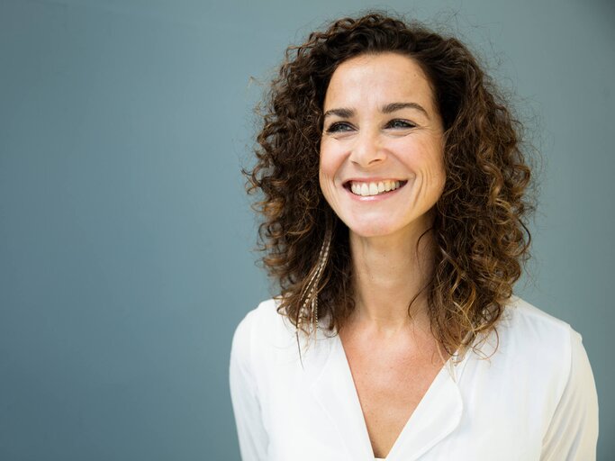 Frau mit Locken hat ein strahlendes Lächeln | © gettyimages.de /  Westend61