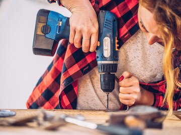Frau verwendet Bohrmaschine | © Getty Images/CasarsaGuru