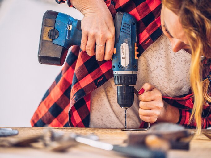 Frau verwendet Bohrmaschine | © Getty Images/CasarsaGuru