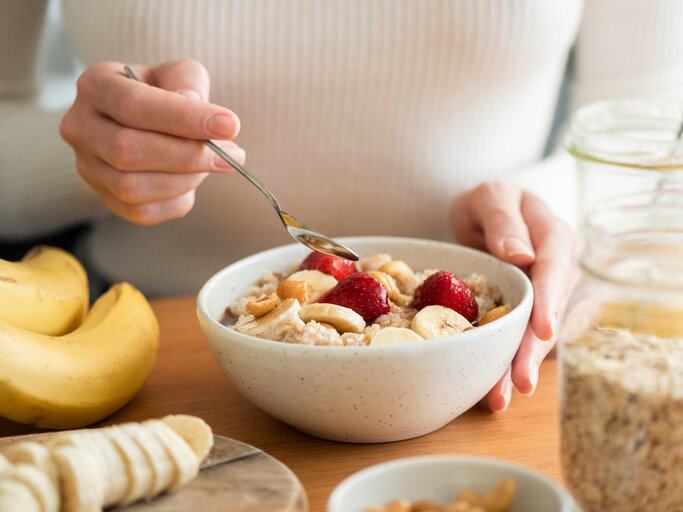 Frau mit einer Schüssel Porridge und Obst | © Getty Images/Arx0nt