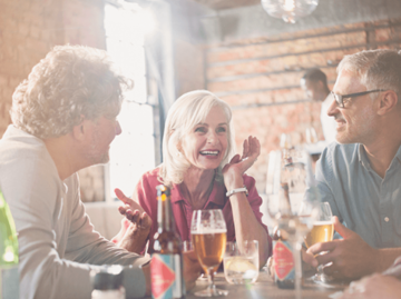 Glückliche Freunde sitzen gemeinsam im Restaurant | © Getty Images | Hoxton, Tom Merton