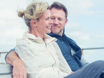 Glückliches Paar auf einer Parkbank | © Getty Images | courtneyk