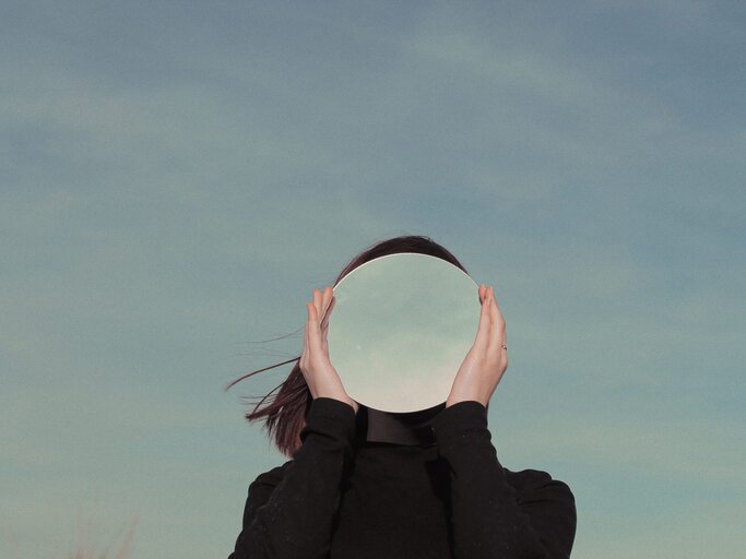 Frau hält sich einen Spiegel vor das Gesicht | © Getty Images/Maria Maglionico / EyeEm