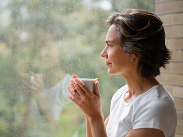 Frau blickt nachdenklich aus dem Fenster | © Getty Images/	Hispanolistic