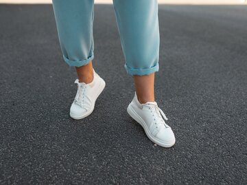 Weibliche Beine mit weißen Sneaker | © Getty Images/Ales_Utovko
