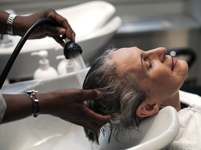 Reife Frau bekommt vom Friseur, die Haare gewaschen | © Getty Images/Allison Michael Orenstein