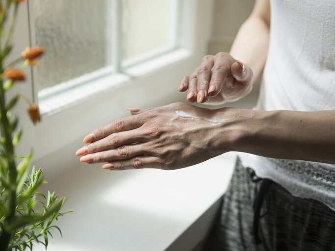 Reife Frau cremt ihre Hände ein | © Getty Images/	Dreet Production