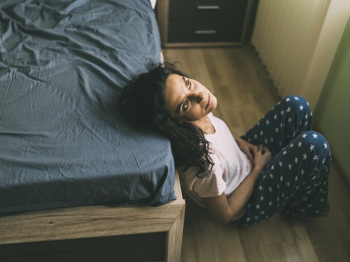 Frau sitzt mit Schuldgefühlen am Bett | © Getty Images/Vladimir Vladimirov