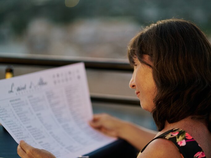 Frau sitzt im Restaurant und studiert das Menü | © Getty Images/	aire images