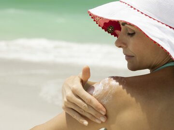 Frau cremt sich in der Sonne ein | © GettyImages/	PhotoAlto/Frederic Cirou