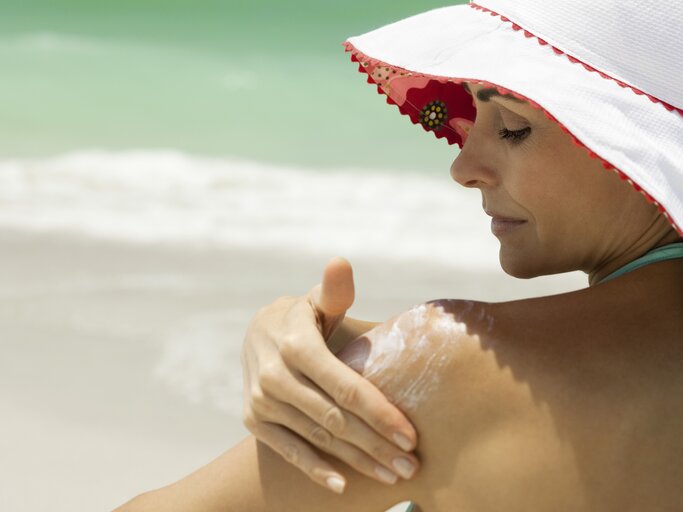 Frau cremt sich in der Sonne ein | © GettyImages/	PhotoAlto/Frederic Cirou