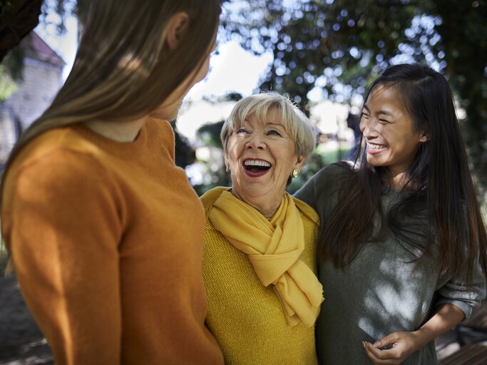 Ältere Frau unterhält sich mit zwei jungen Frauen | © Getty Images/Oliver Rossi