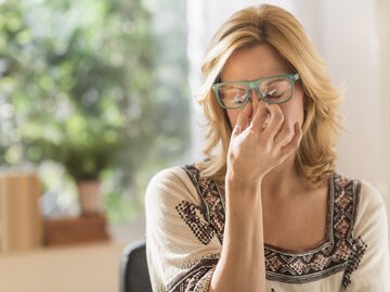 Reife Frau ist gestresst und körperlich erschöpft | © Getty Images/	Tetra Images