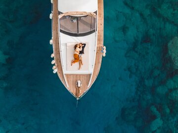 Paar liegt auf einem Boot im weiten Meer | © Getty Images/	Oleg Breslavtsev