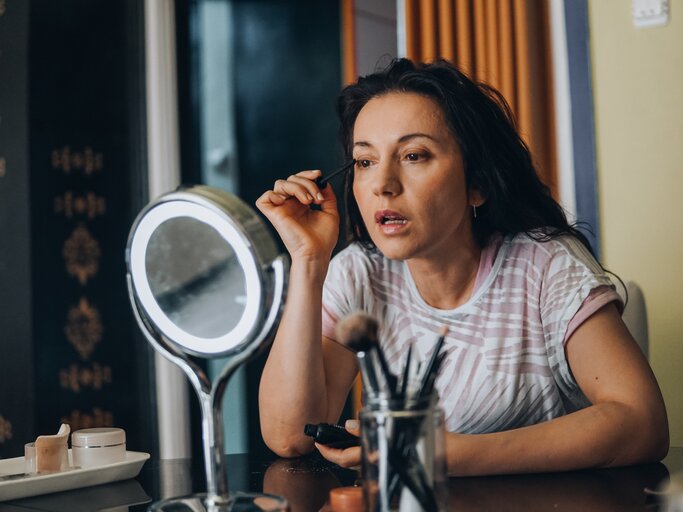 Frau schminkt sich im Spiegel | © Getty Images/	Milshot