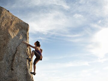 Frau klettert Felswand hinauf | © GettyImages/	Klaus Vedfelt