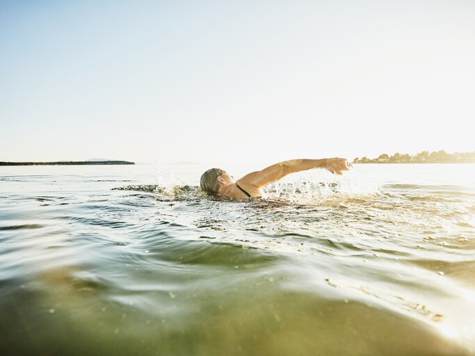 Frau geht im See schwimmen | © Getty Images/Thomas Barwick