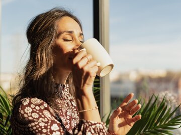 Frau trinkt in der Sonne einen Kaffee | © Getty Images/Raul Ortin