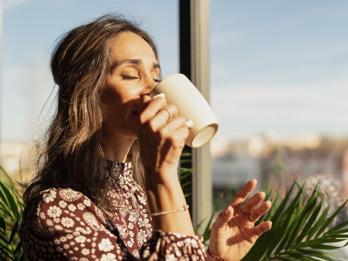 Frau trinkt in der Sonne einen Kaffee | © Getty Images/Raul Ortin