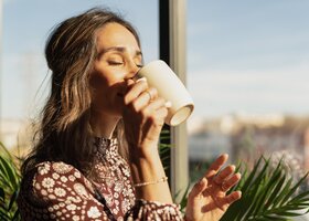 Frau trinkt in der Sonne einen Kaffee