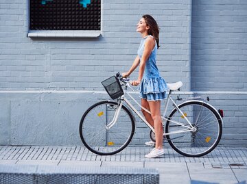 Frau im Kleid fährt Fahrrad | © Getty Images/	BartekSzewczyk