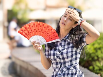 Frau fächert sich kühle Luft zu während Sommerhitze | © Getty Images/	SimpleImages