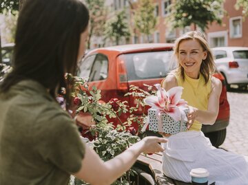 Frau schenkt ihrer Freundin einen Blumenstrauß | © Getty Images/Westend61