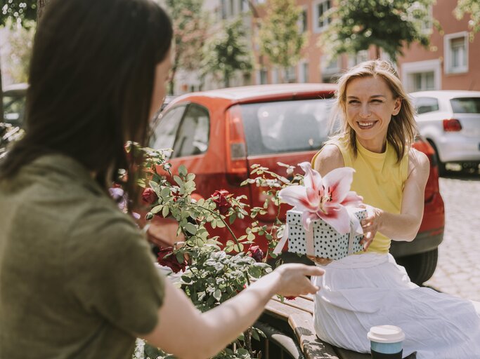 Frau schenkt ihrer Freundin einen Blumenstrauß | © Getty Images/Westend61