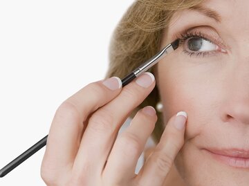 Reife Frau schminkt sich mit Eyeliner | © Getty Images/Glow Images
