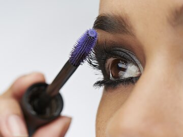 Frau mit braunen Augen tuscht sich die Wimpern | © GettyImages/Klaus Vedfelt